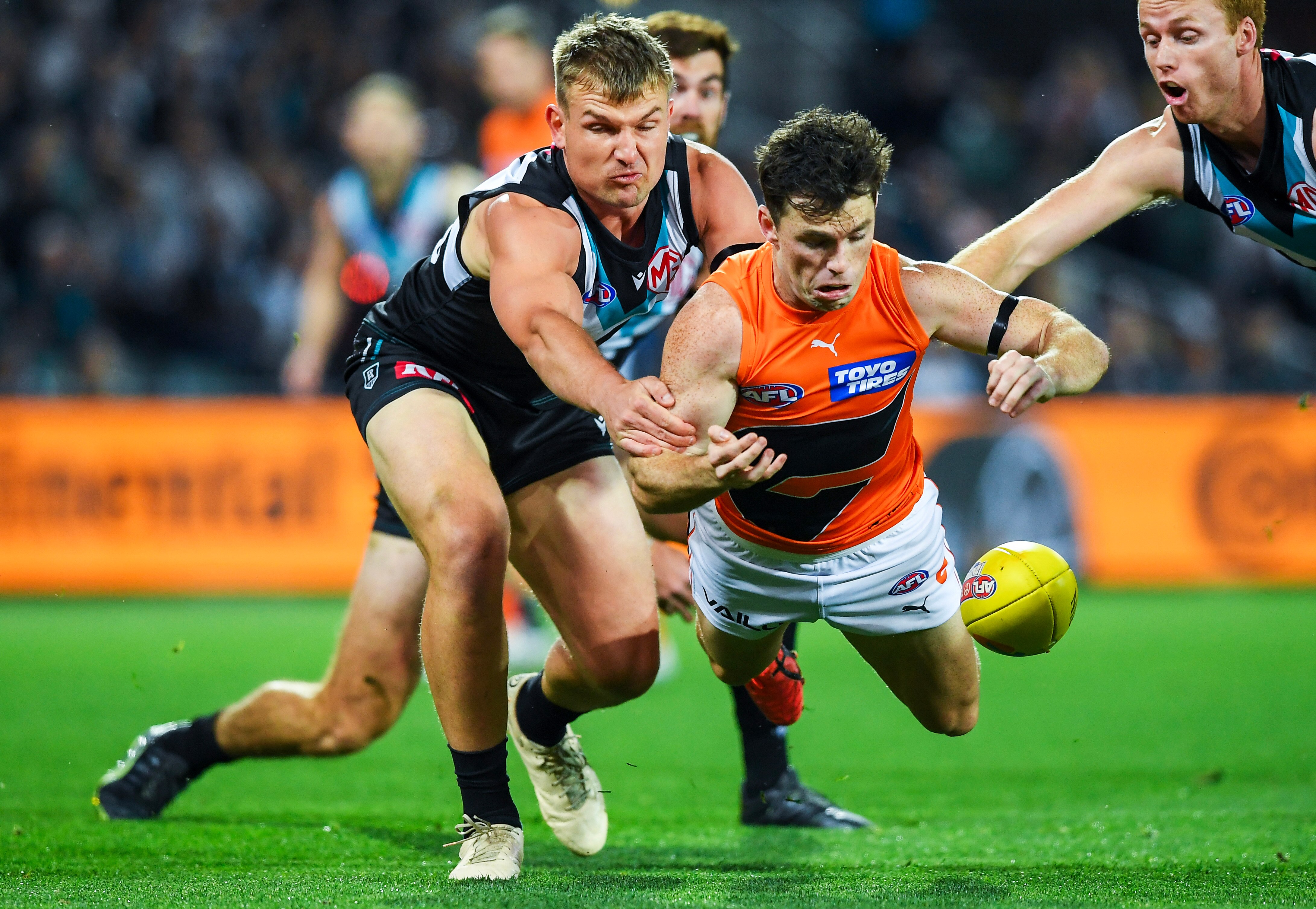 Brent Daniels of GWS dives for a ball as Port Adelaide's Ollie Wines pursues during an AFL semifinal.
