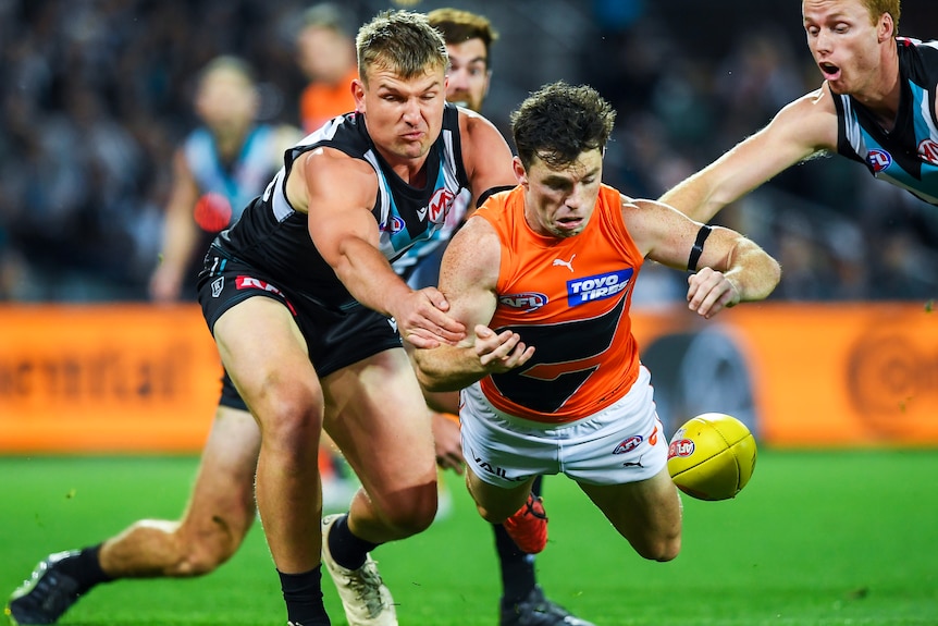 Brent Daniels of GWS dives for a ball as Port Adelaide's Ollie Wines pursues during an AFL semifinal.