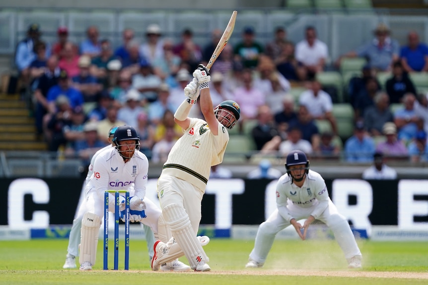 Travis Head follows through after hitting a ball high into the air as England players look on