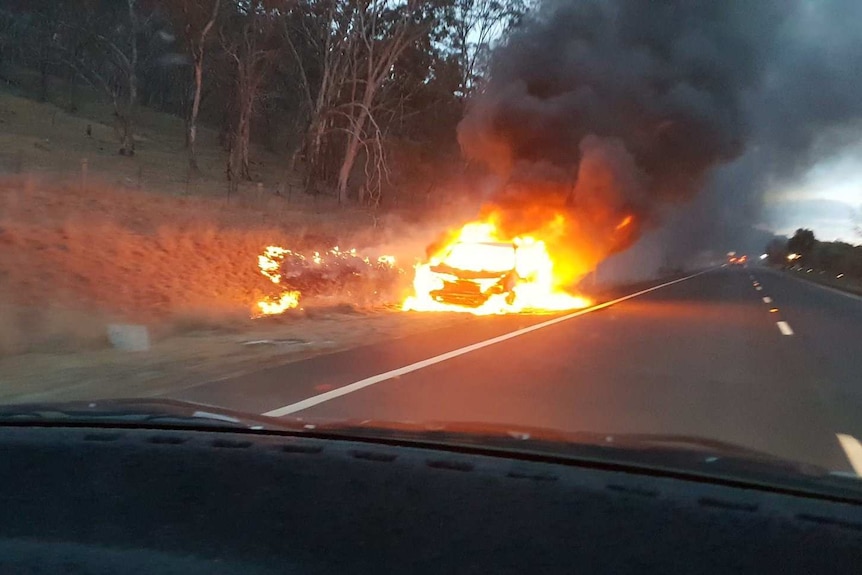 A car is engulfed in flames beside the Monaro Highway in New South Wales, near Michelago.