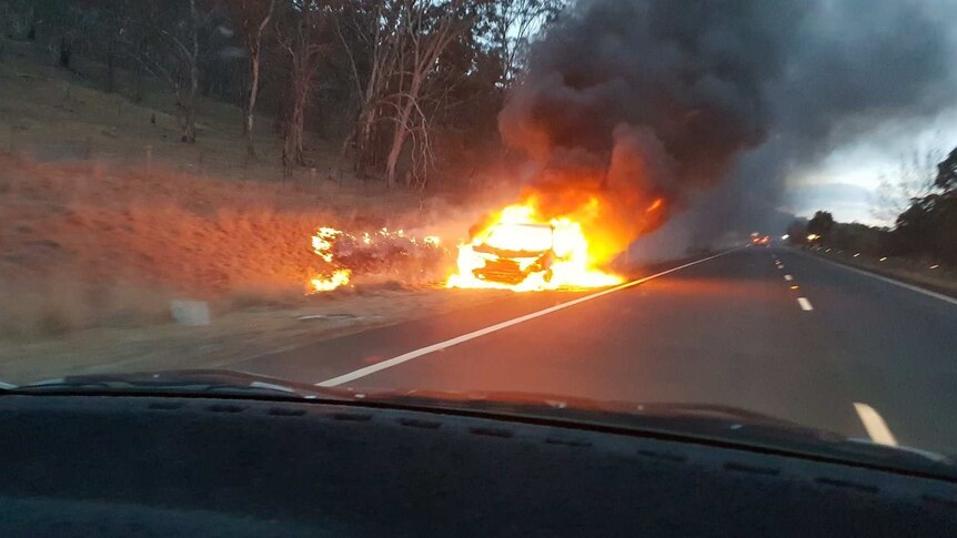 A car is engulfed in flames beside the Monaro Highway in New South Wales, near Michelago.