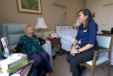 A 93-year-old woman and a younger nurse smiling and laughing in an aged care facility room.