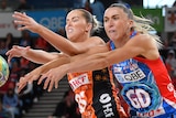 A Giants Super Netball player contest for the ball alongside a Swifts opponent.