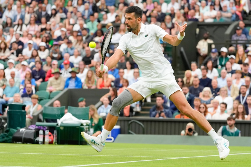 Serbian tennis star Novak Djokovic, wearing a brace on his right knee, lunges forward to play a shot at Wimbledon.