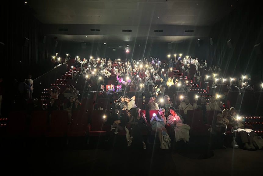 Movie theater with people holding lights and posing for a picture