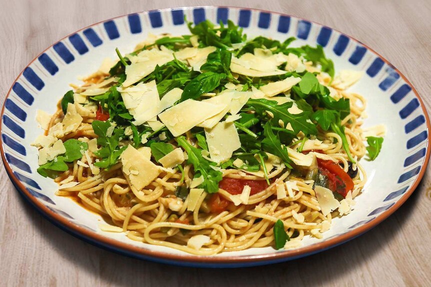 A bowl of vegetarian spaghetti topped with rocket and parmesan cheese, an easy homemade dinner.