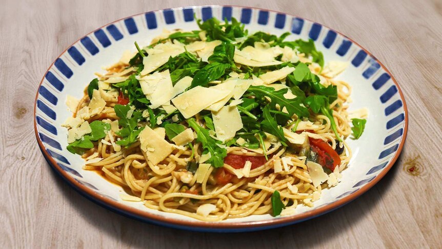 A bowl of vegetarian spaghetti topped with rocket and parmesan cheese, an easy homemade dinner.