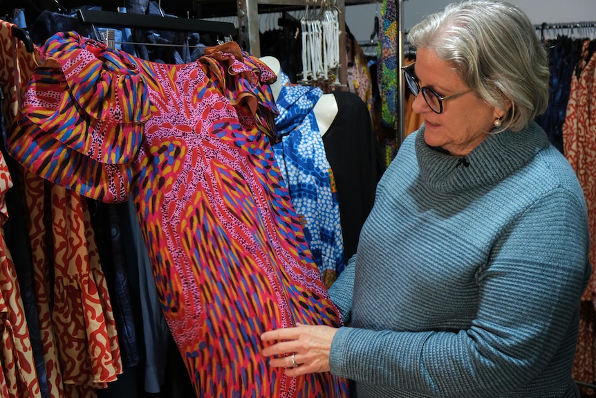 Amanda Haley looks at a pink evening gown with a local print on it.