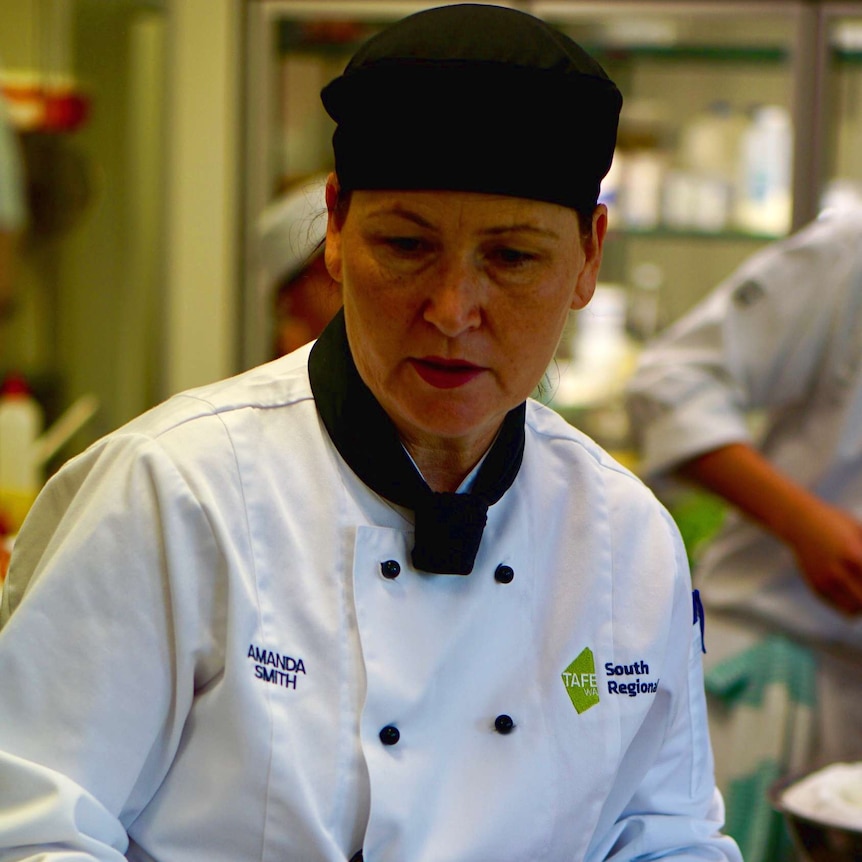 Chef in the kitchen teaching her apprentices