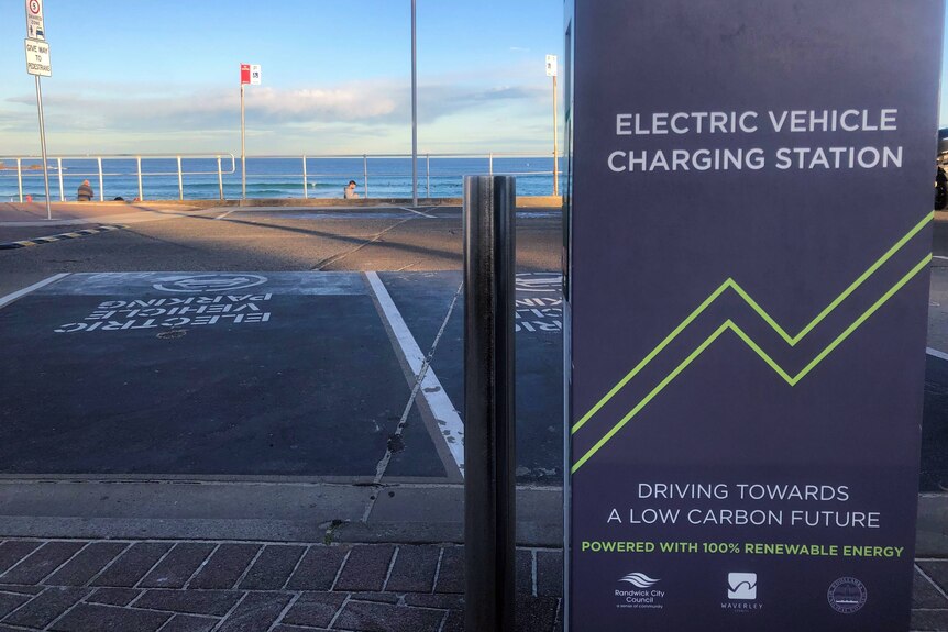 A beach with an electric vehicle charger in the foreground