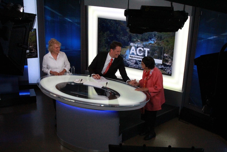 Elders standing at news desk with newsreader Dan Bourchier.