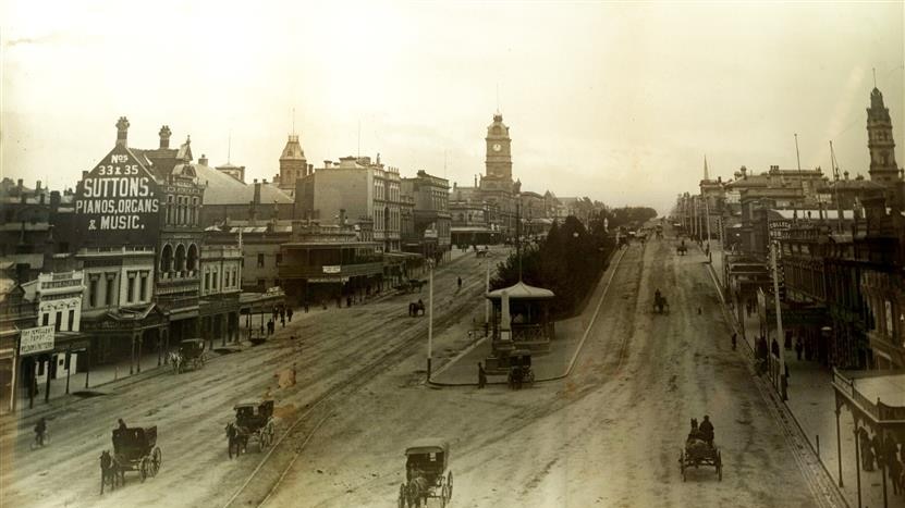 black and white photo of old street with horses and carriages