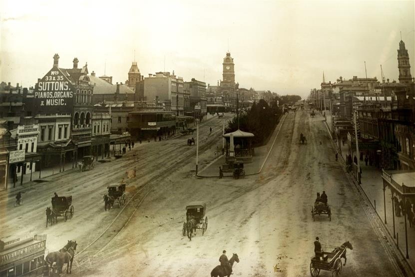 black and white photo of old street with horses and carriages