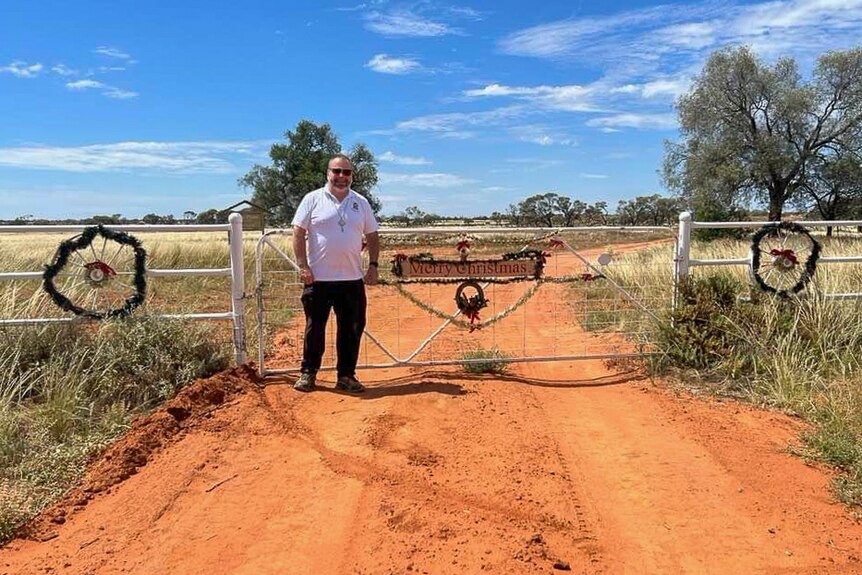 a man stands at a farm gate