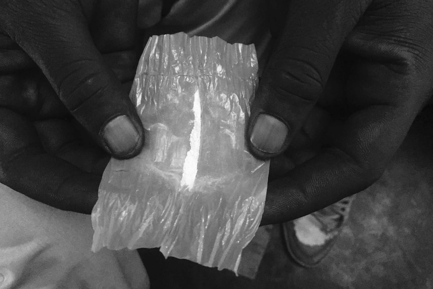 Hands hold a piece of foil with a white powder in it.