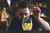 Sean Baxter uses tweezers to add a garnish to a gin and tonic.