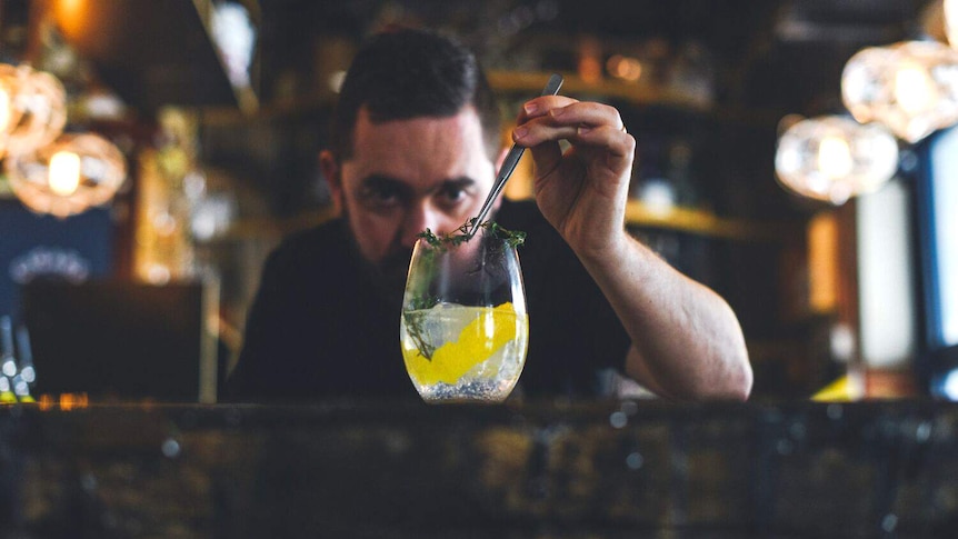 Sean Baxter uses tweezers to add a garnish to a gin and tonic.