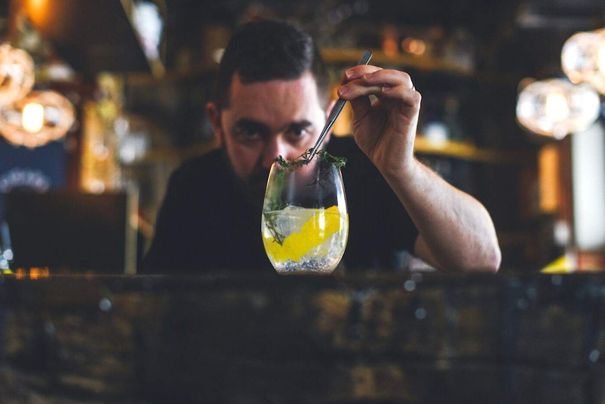 Sean Baxter uses tweezers to add a garnish to a gin and tonic.