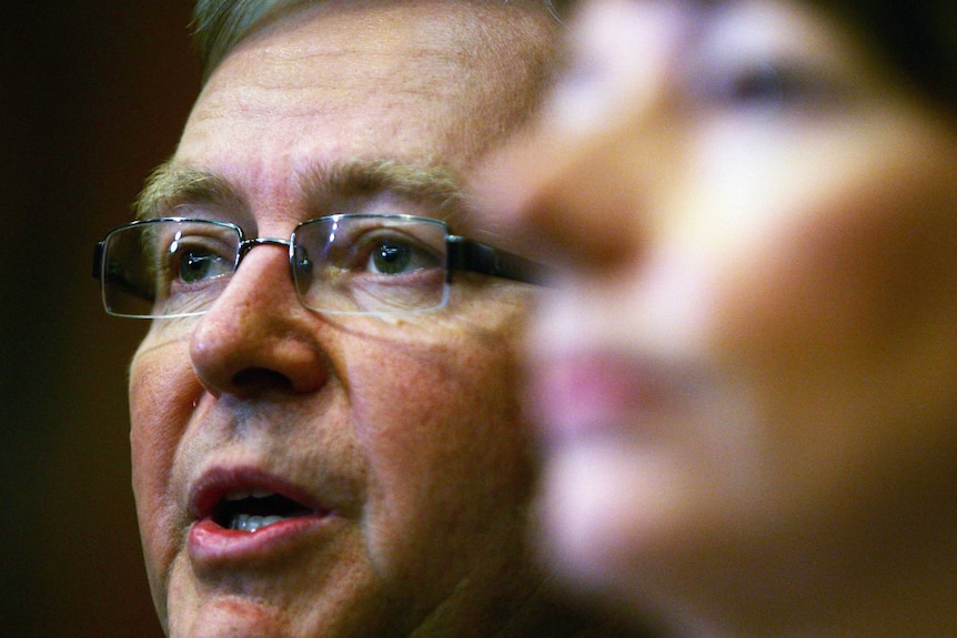 Kevin Rudd speaking while Julia Gillard is blurred in the foreground.