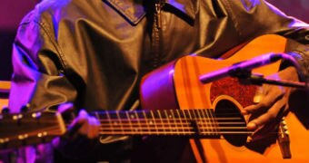 A close up of Dr G Yunupingu's hands on his guitar as he performs in London.