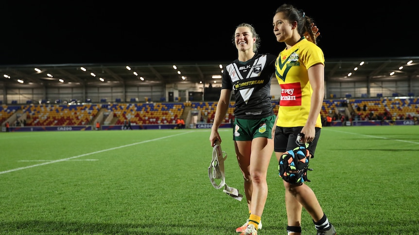 Emma Tonegato in a New Zealand jersey embraces Page McGregor, in a Jillaroos jersey, after their World Cup match.