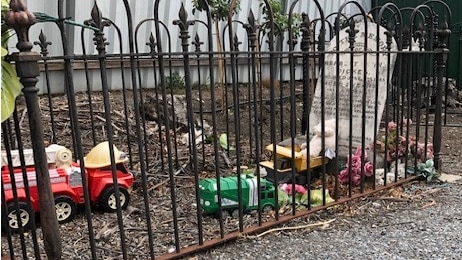 Toys on a grave surrounded by a small fence