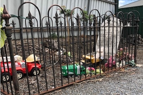 Toys on a grave surrounded by a small fence