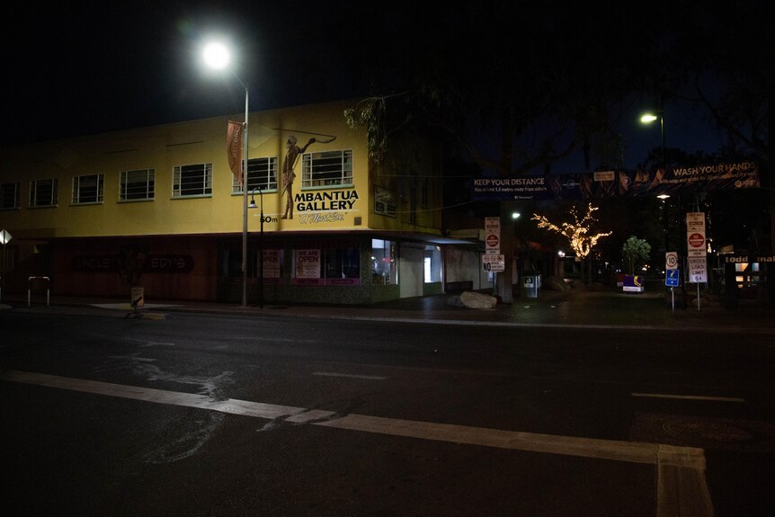 In a darkened Alice Springs CBD, a street light illuminates an Aboriginal art gallery and part of the Mall next to it