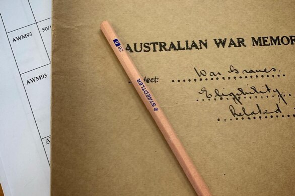 Close of a beige file with Australian war memorial in black written on it. Pencil rests on top.