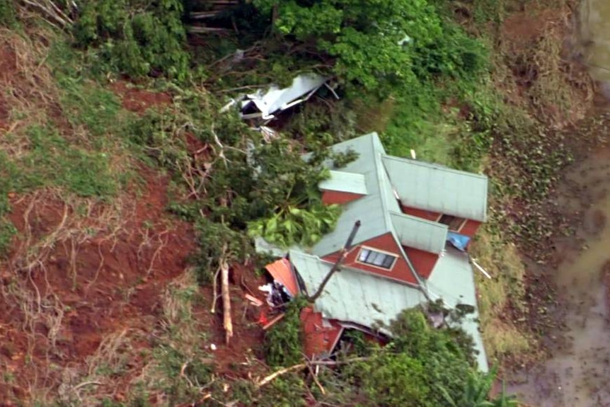 A house falling down the side of a red hill