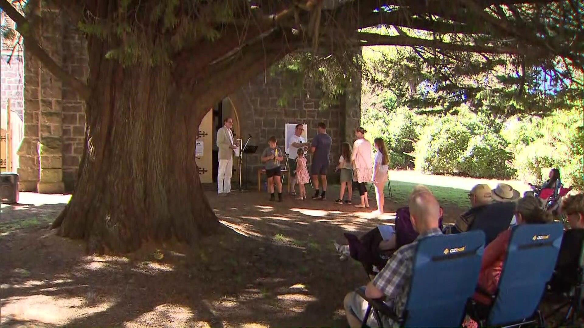 People sit in chairs for outside church service.
