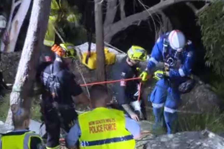 A group of emergency services workers gather on a cliff