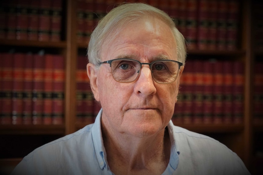Justice Graham Hiley, an elderly male with glasses, looks at the camera sincerely.