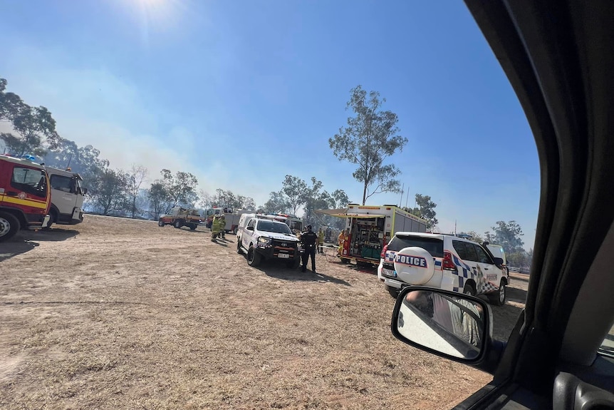 Police and fire trucks parked near a bushfire.