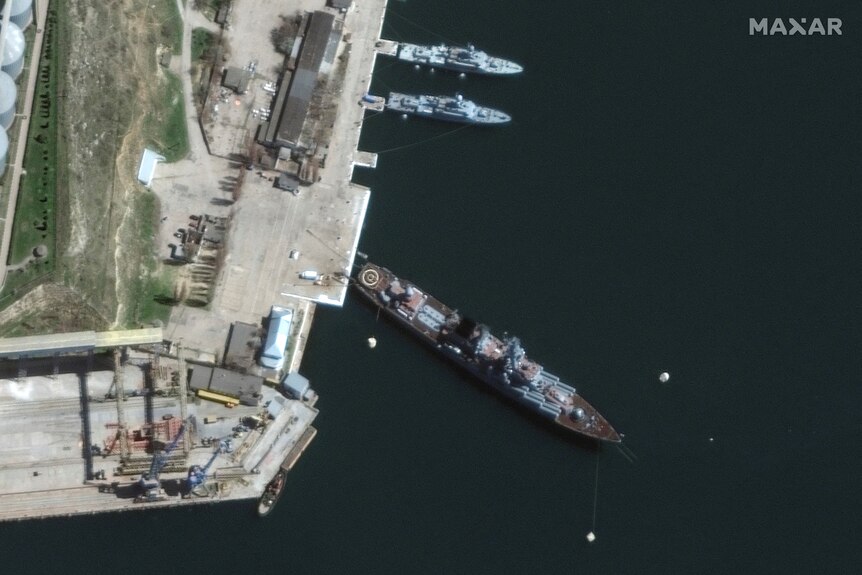 A satellite image showing a large port, where one large ship and two smaller ships have docked.