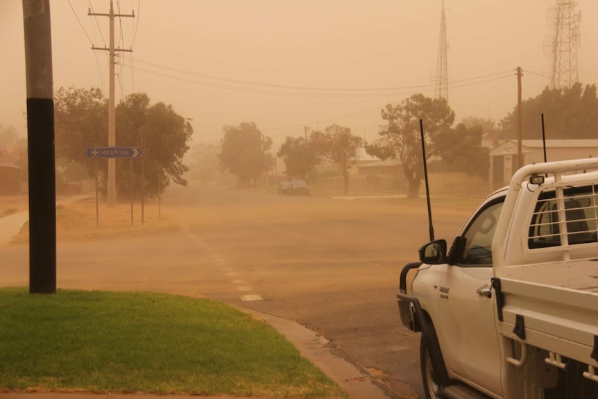 A ute on a road surrounded by dust.