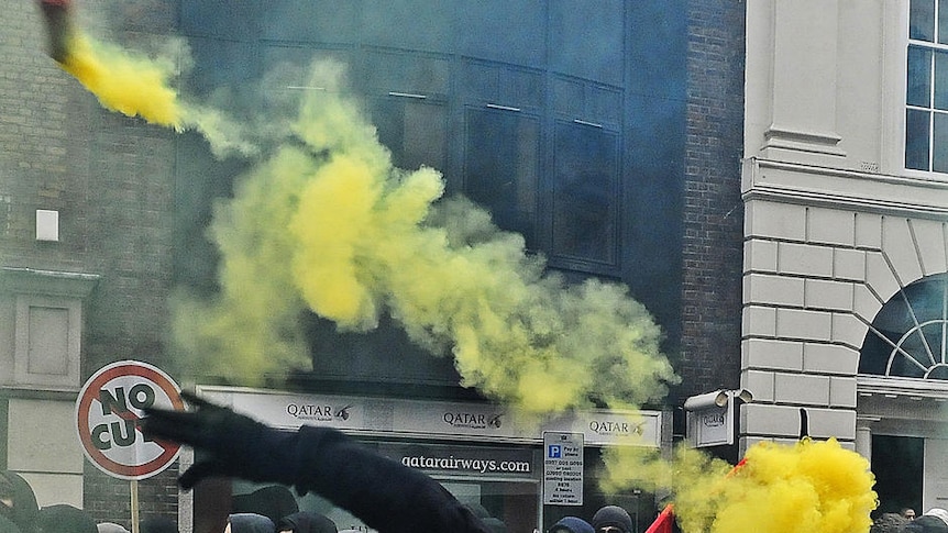 A protester throws a yellow smoke bomb