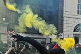 A protester throws a yellow smoke bomb