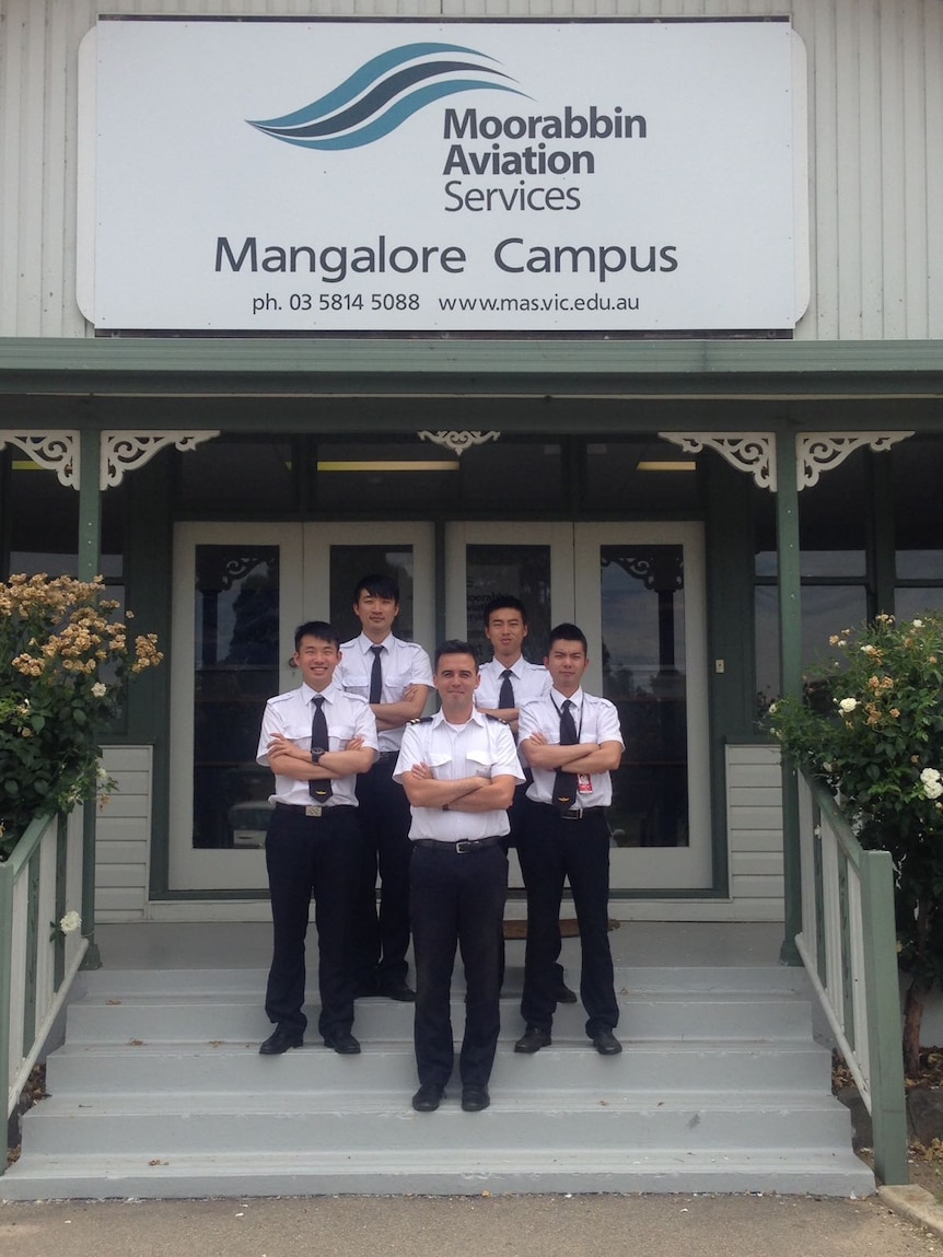 Four pilots standing with arms crossed outside the Mangarlore pilot training school