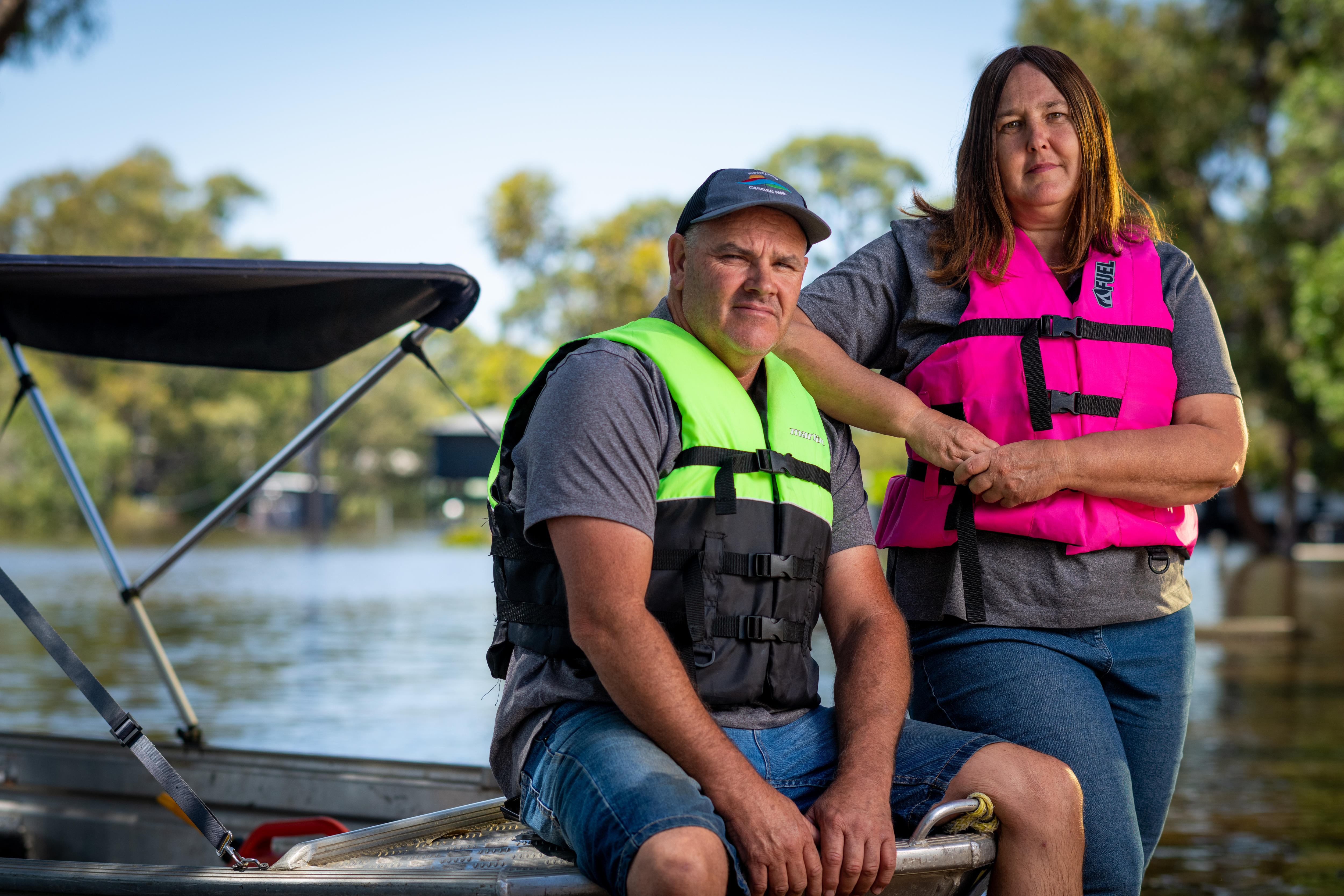 A man and a woman wearing lifejackets next to a boat