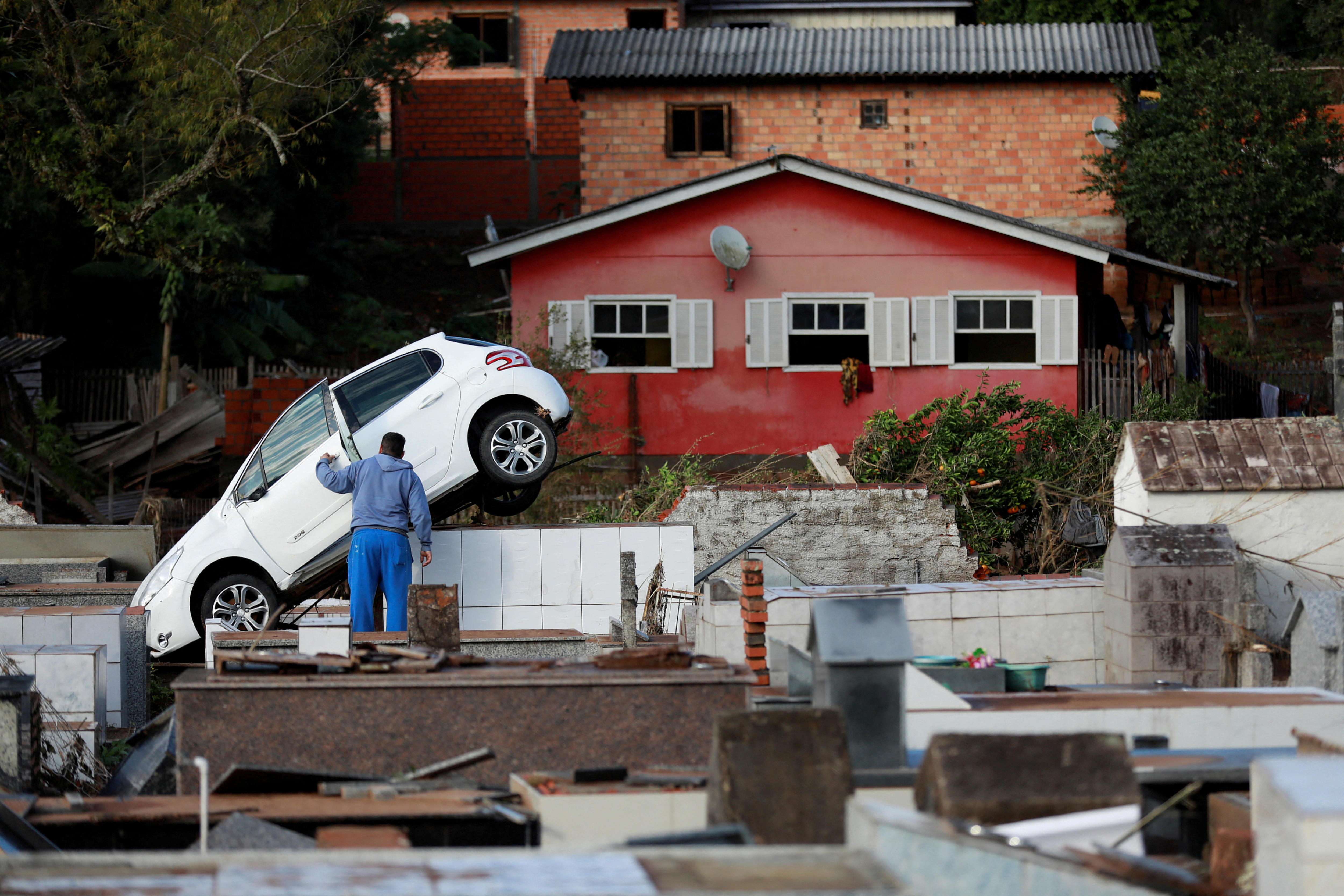 A man stands next to a car which came to rest on top of graves.