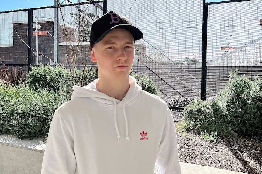 A young man wearing a cap and hoodie.