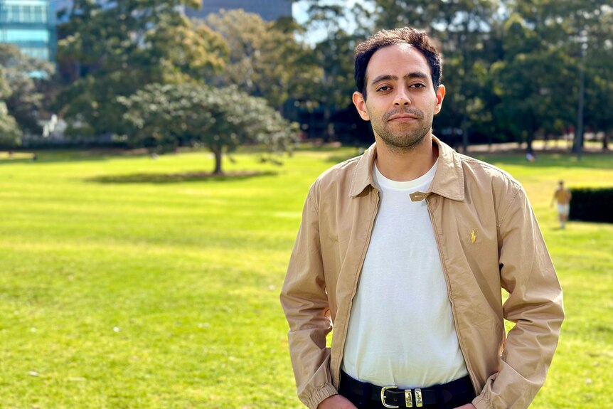 Fahad Ali standing on grass in a brown jacket