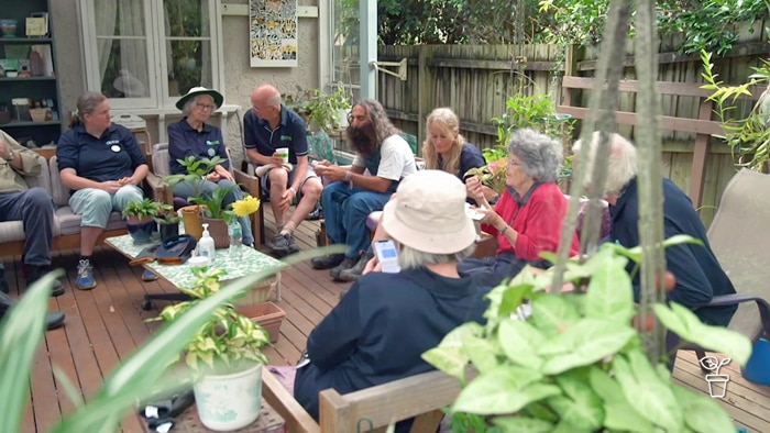 Group of people sitting on a verandah having morning tea