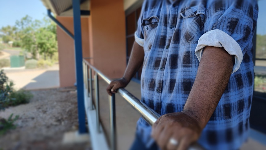 An unidentified man stands, holding bars in front of him