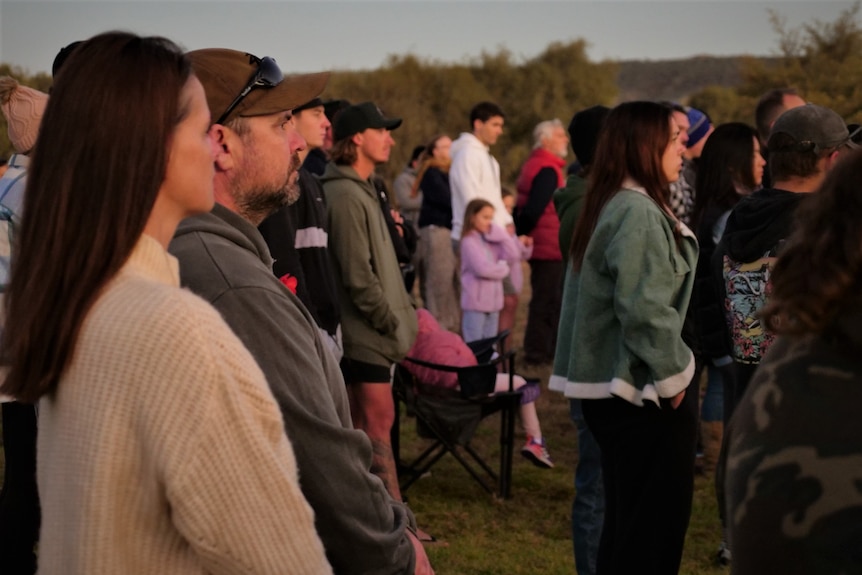 A group of people in jumpers stand in a crowd.