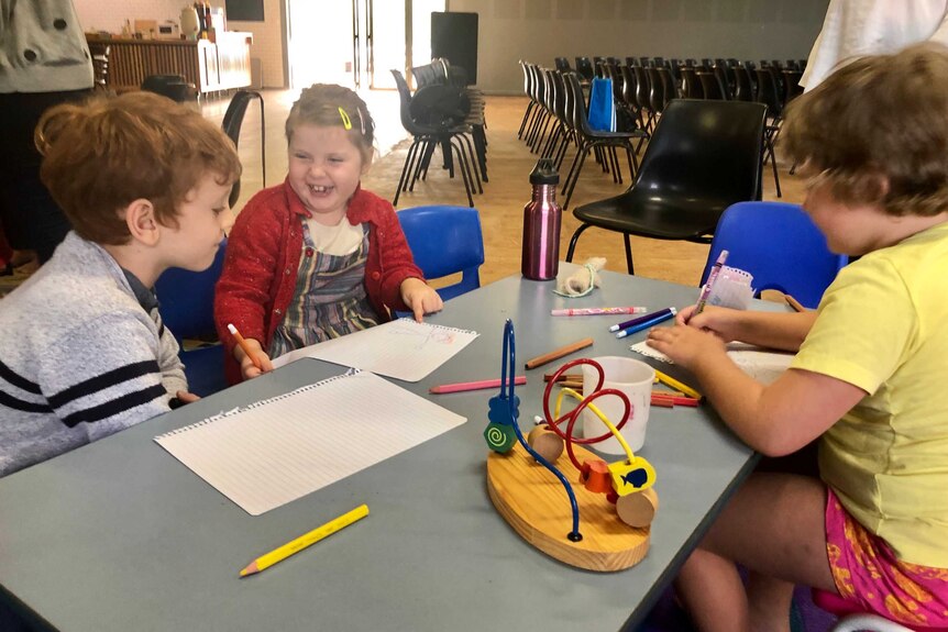 Children sit at a table drawing.