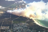 An aerial photo of a bushfire burning towards a coastline