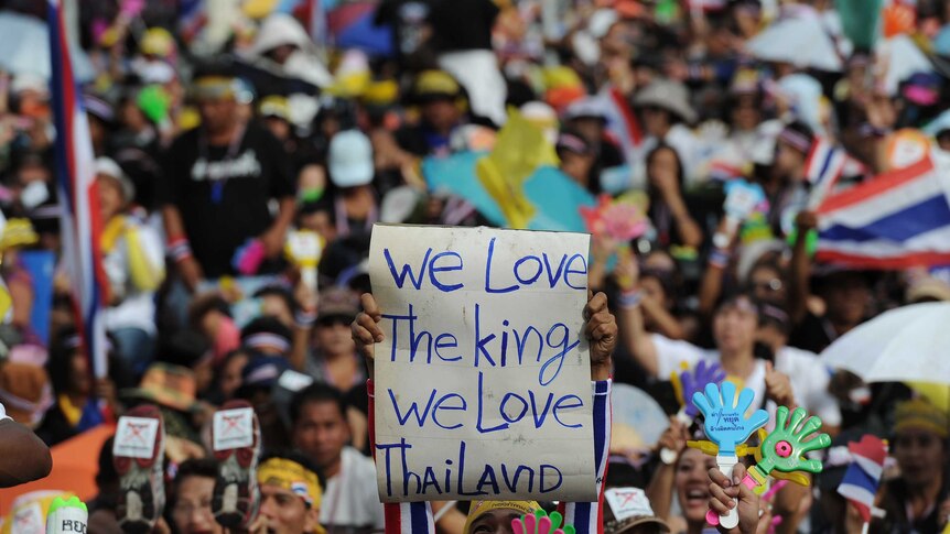 A Thai opposition protester holds up a sign