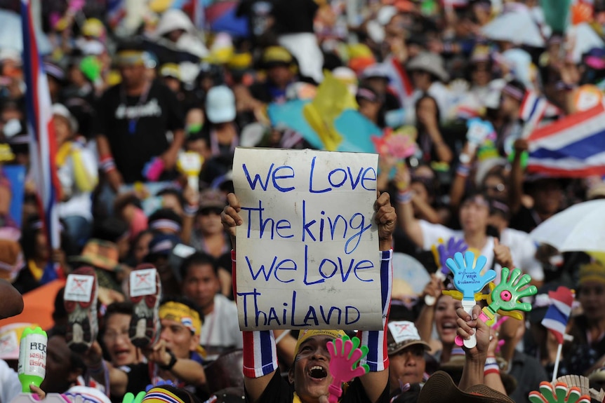 A Thai opposition protester holds up a sign